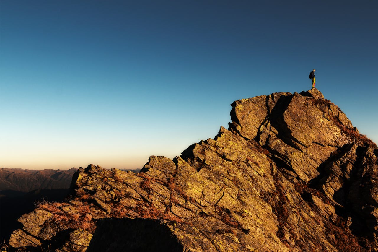 Man Standing on Top of Rock at Daytime